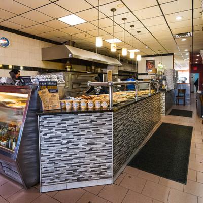 Restaurant counter with pizza display and hanging lights.