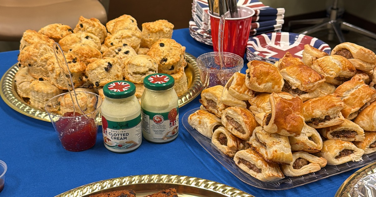 Tea party spread featuring scones served with clotted cream and jam, alongside sausage rolls