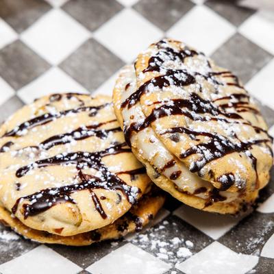 Cookie Nolis drizzled with chocolate and topped with powdered sugar.