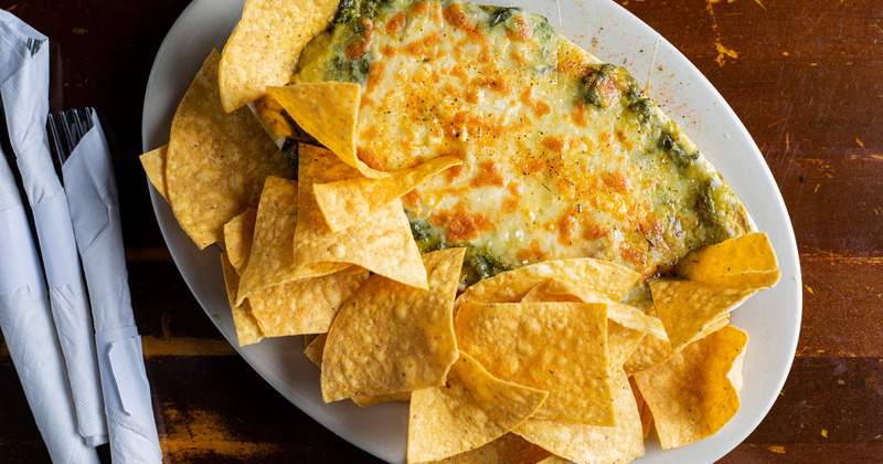 Tortilla chips with a cheese and greens dip, top view