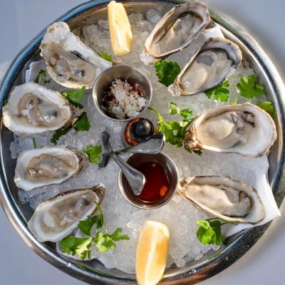 Fresh oysters on ice with lemon wedges and dipping sauces.