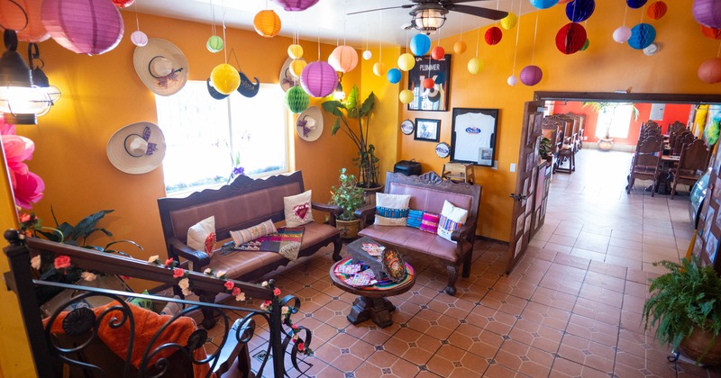 Cozy indoor space decorated with colorful lanterns, wooden furniture, and sombreros on an orange wall