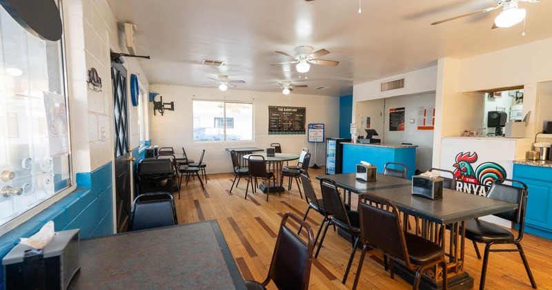 Interior with black tables, chairs and blue counter with a rooster logo