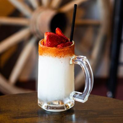 Creamy cocktail in a glass mug with strawberries and chili rim.