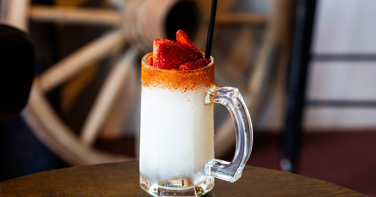 Creamy cocktail in a glass mug with strawberries and chili rim
