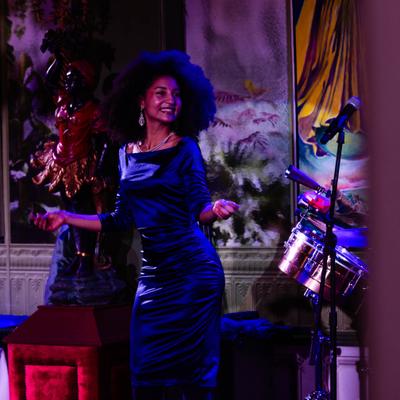 Live performance with singer dancing with colorful artwork in the background.