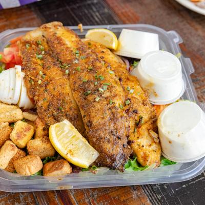 Grilled Fish Salad served with three dressings and a lemon wedge.