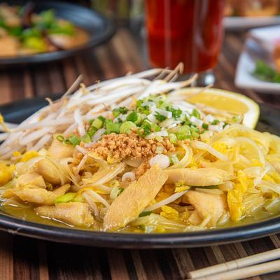 Chicken noodle dish topped with bean sprouts, peanuts, and scallions.