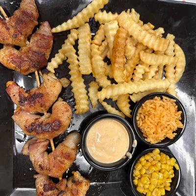 Bacon-wrapped shrimp served with crinkle-cut fries, rice, corn and a dipping sauce.