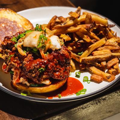 Fried chicken sandwich, with chili sauce, passion fruit, onion, scallions and fries.