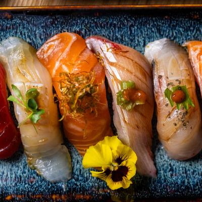 Overhead view of mixed nigiri sushi with various toppings and flower garnish.