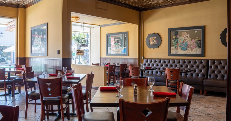 Restaurant interior with wooden tables set with red napkins and glassware