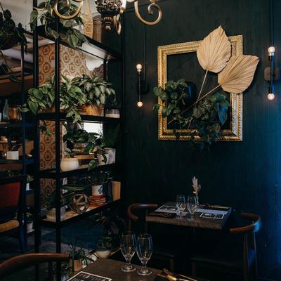 Cozy corner with set tables, lush plants, and wall art.