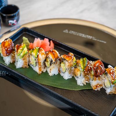 Dragon Roll featuring eel and avocado top, garnished with sesame seeds.