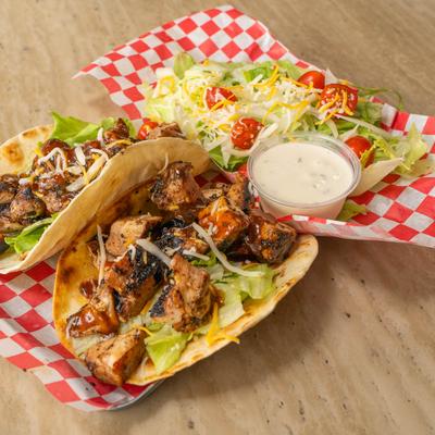Caribbean jerk chicken tacos served with a salad and creamy dressing.