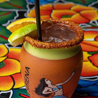Cantarito cocktail in a chili-rimmed clay cup with citrus garnish.