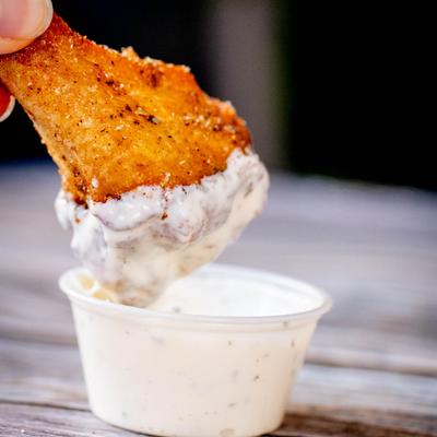 Dry rub wing in dip, close up.