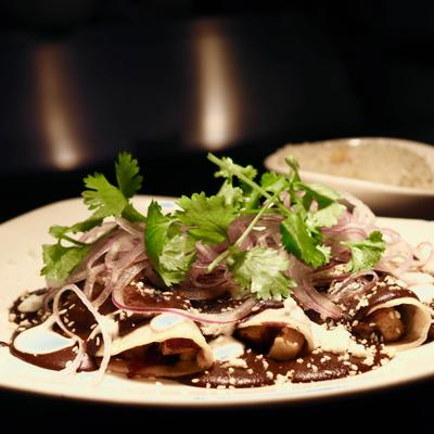 Enchiladas in mole sauce toped with sliced red onions and fresh cilantro.