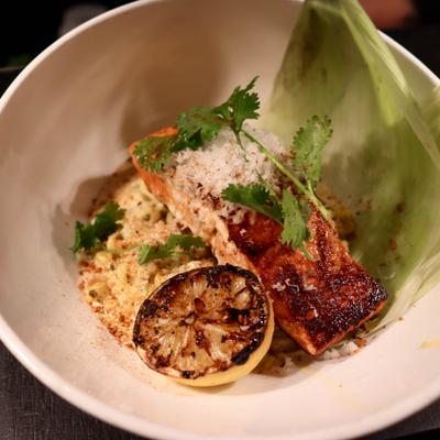 Grilled salmon on a bed of rice, served with lettuce leafs and grilled lemon.