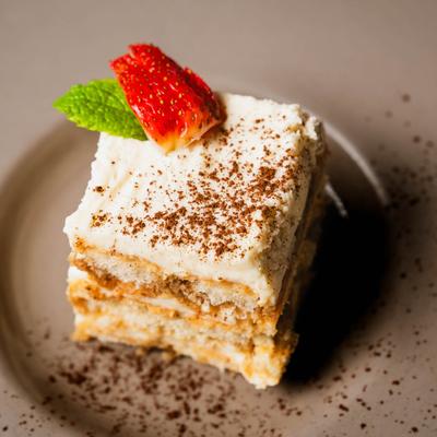 Tiramisu garnished with cinnamon, strawberry and a mint leaf.