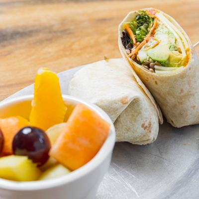 Avocado hummus wrap with fresh fruit on the side.