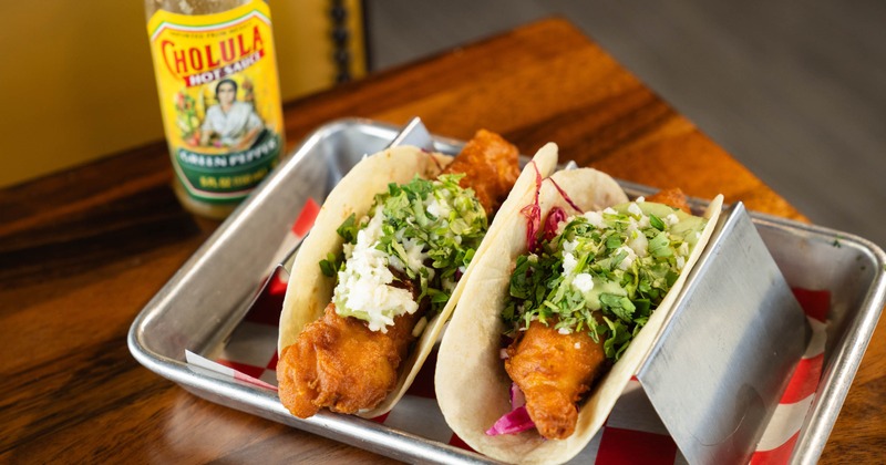 Crispy fried fish tacos served on soft flour tortillas in a metal taco holder