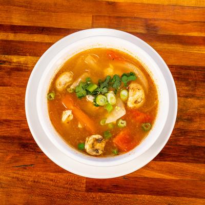 Spicy lemongrass soup with onion, mushroom, tomato and cilantro, top view