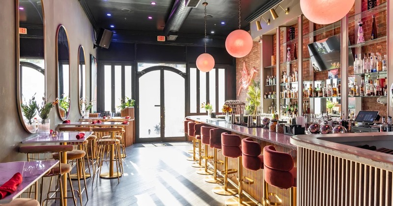 Cozy interior space with a bar on the right side and high dining tables and stools on the left side