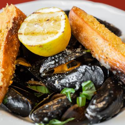 Steamed mussels served with lemon half and bread.