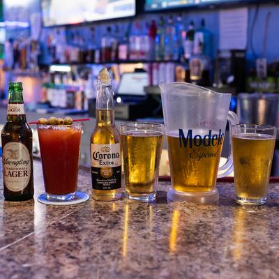 Pitcher of beer served alongside glasses, two bottles of beer and a Michelada cocktail.