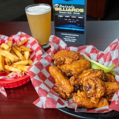 Chicken wings with fries and a glass of beer.