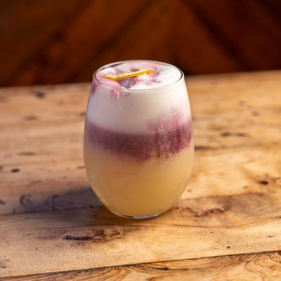 Whiskey sour cocktail served on a wooden table.
