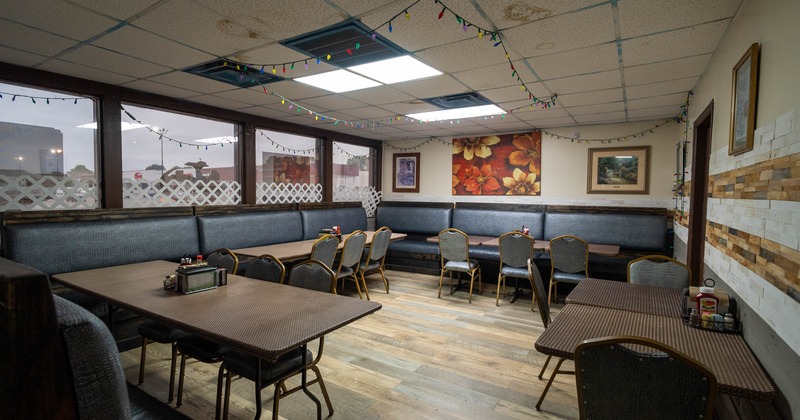 Interior - dark wood tables, padded chairs, festive string lights, paintings and large windows.