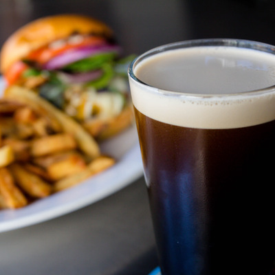 A glass of Stout beer, with burger and fries photo.