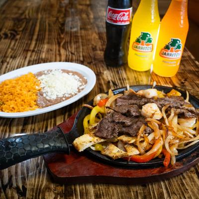 Chicken, shrimp, and steak Fajitas, with grilled onions, bell peppers, rice, and beans.