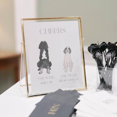 Cheers signage, envelopes, and drink stirrers on a white table, close up.