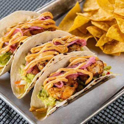 Shrimp Tacos topped with a spicy sauce and pickled red onions.
