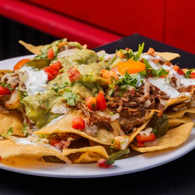Loaded nachos topped with birria, diced vegetables, sour creme and guacamole.