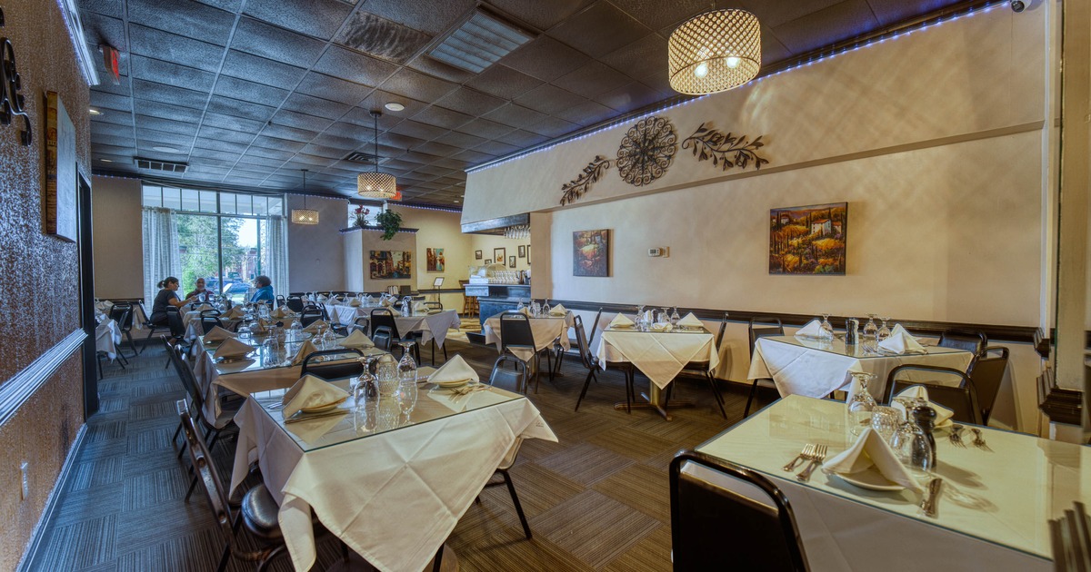 Interior of a restaurant with white tablecloths, elegant light fixtures, and wall art