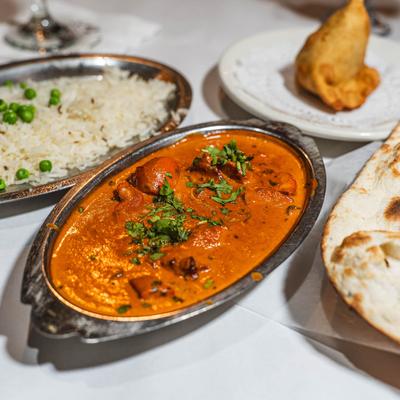 Chicken tikka masala with naan bread, basmati rice with peas, and a samosa.