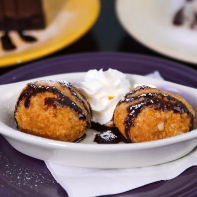 Fried ice cream with chocolate drizzle, powdered sugar and whipped cream.