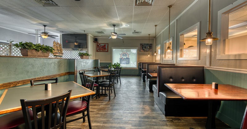 Interior of cozy dining area with tables and chairs, and upholstered booths along the wall
