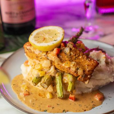 Blackened salmon with mashed potatoes, asparagus, Cajun cream sauce, and veggies.
