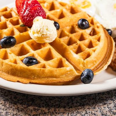 Waffle topped with blueberries, strawberries, and butter, close-up.