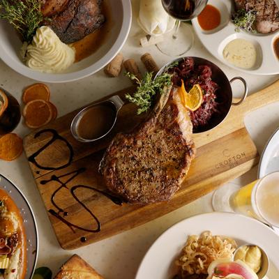Assorted food dishes with Das Dry Age Steak board in the middle of the table.