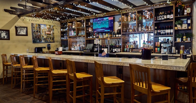 Interior, bar area, massive marble top bar with wooden stools, large drink shelves in the back