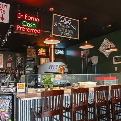 Interior with with counter seating, featured pizza oven and and various signage.