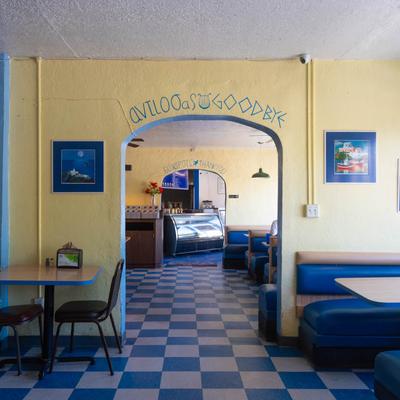 Greek restaurant interior with blue-and-white checkered floors and blue booths.