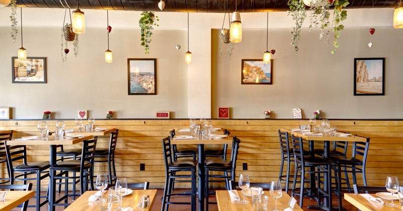 Interior with wooden tables, black chairs, warm lighting, and decorative art on the walls