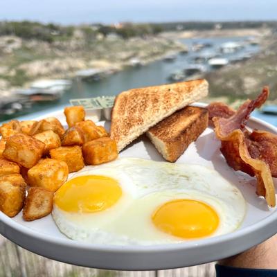 Sunny side up eggs, bacon, potatoes, and toast.